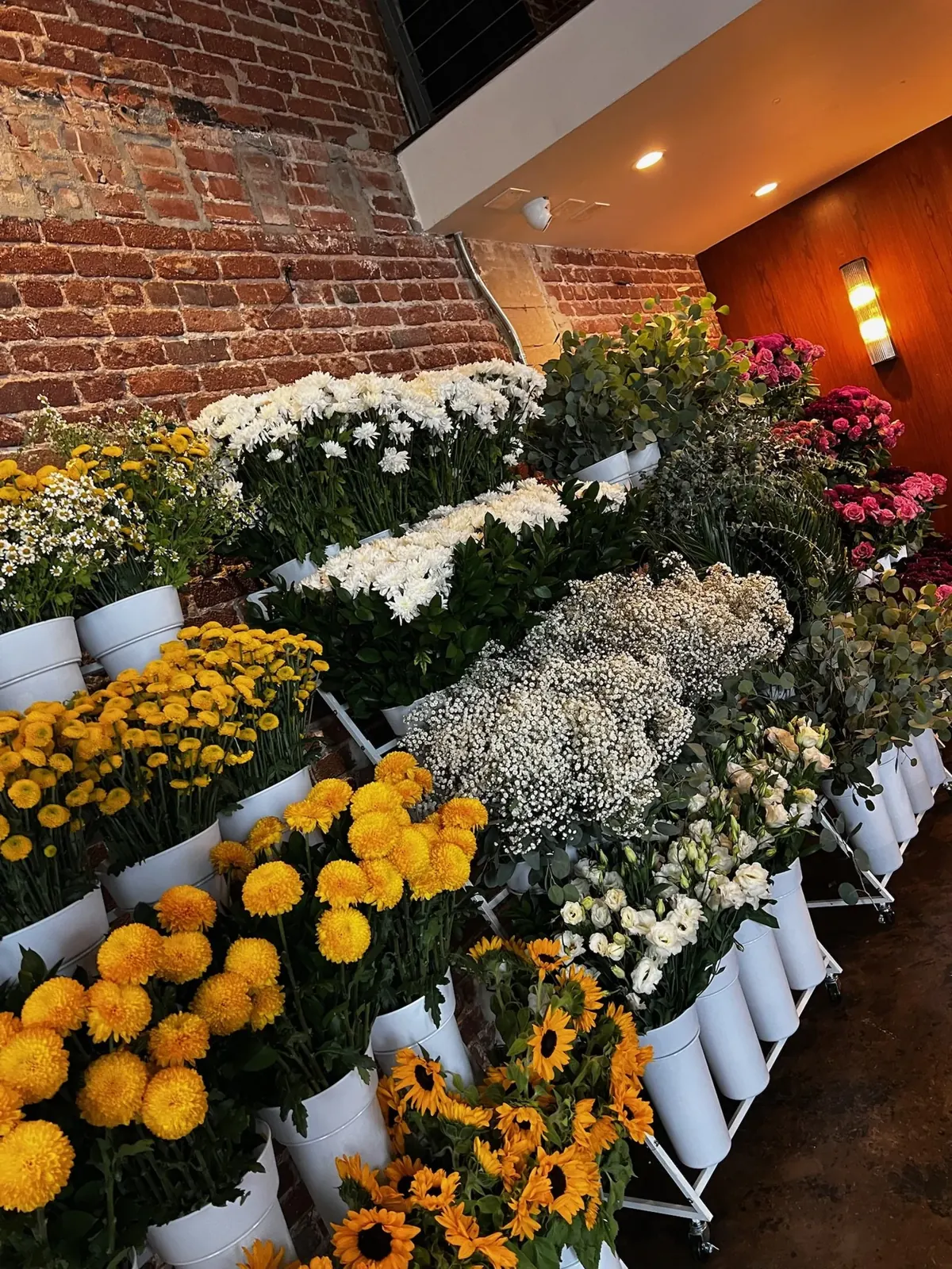A STEMS bouquet bar: buckets of sunflowers, mums, roses and baby's breath on tiered stands